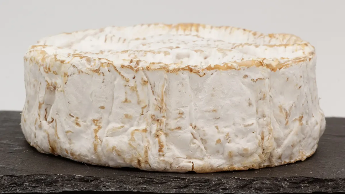A whole Camembert de Normandie cheese with a slice cut out