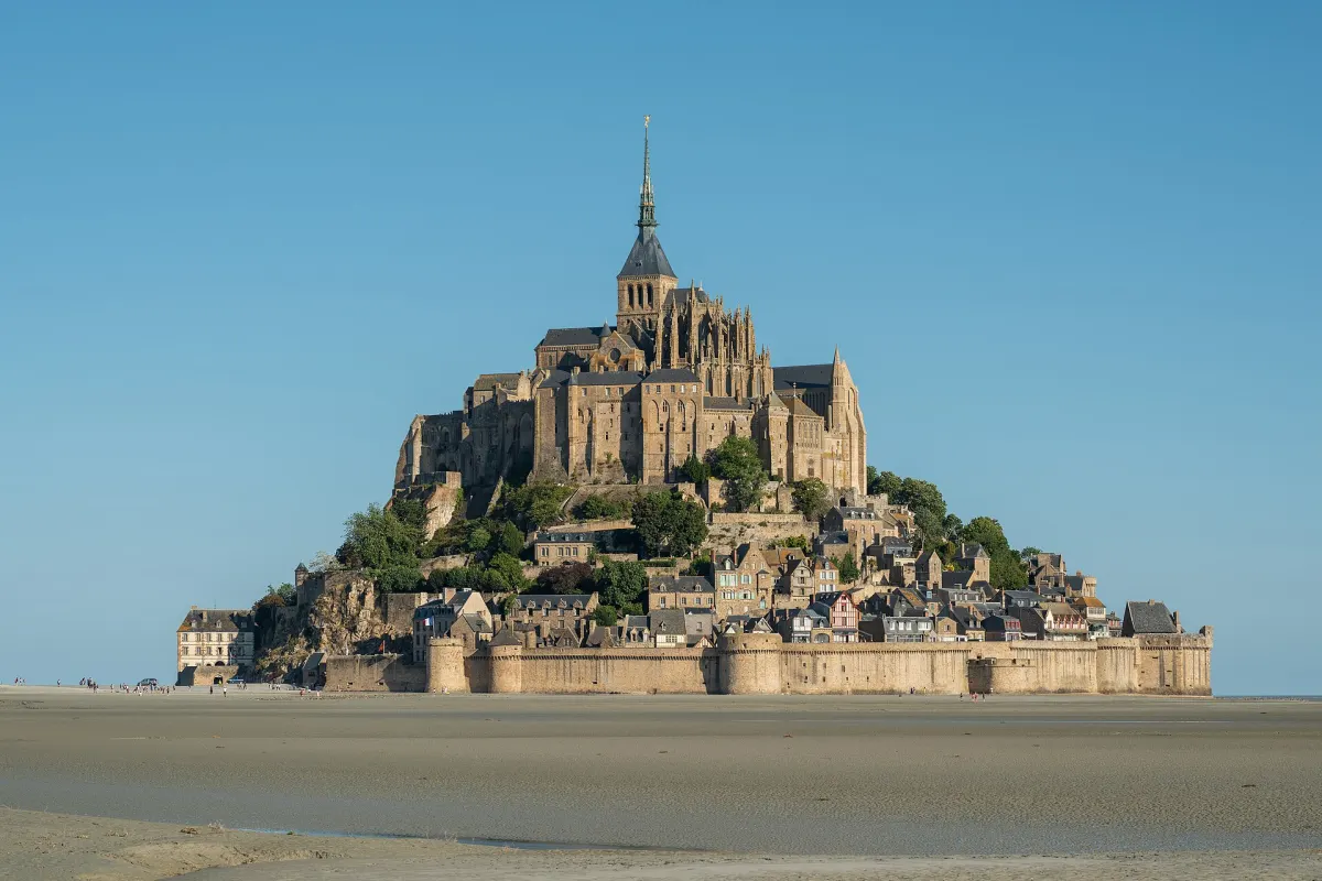 Mont-Saint-Michel abbey standing on its rock at low tide with open sand around it