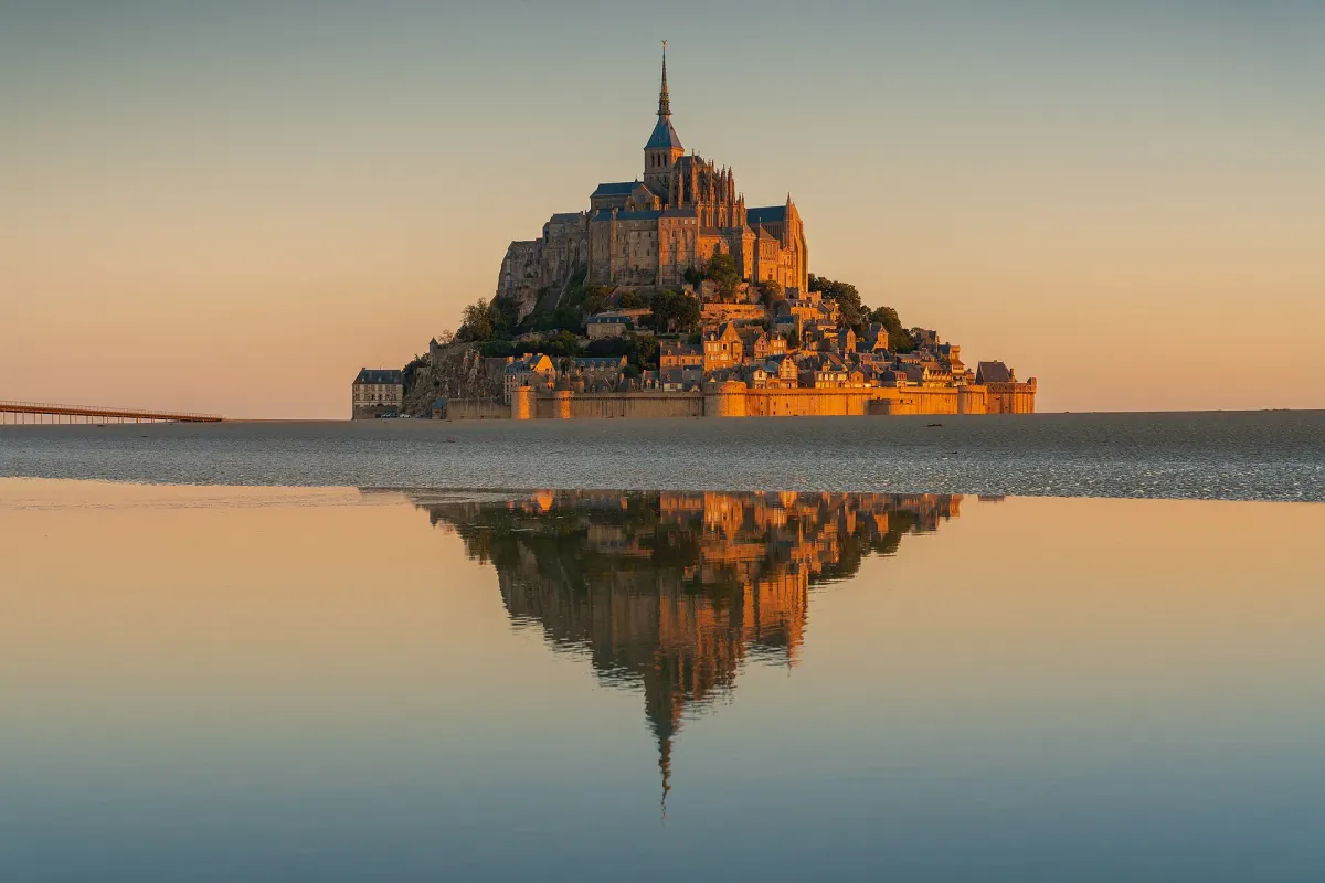 Mont-Saint-Michel abbey at sunrise reflected in the bay, Normandy, France